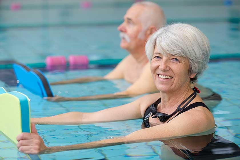 Happy senior couple taking swimming lessons