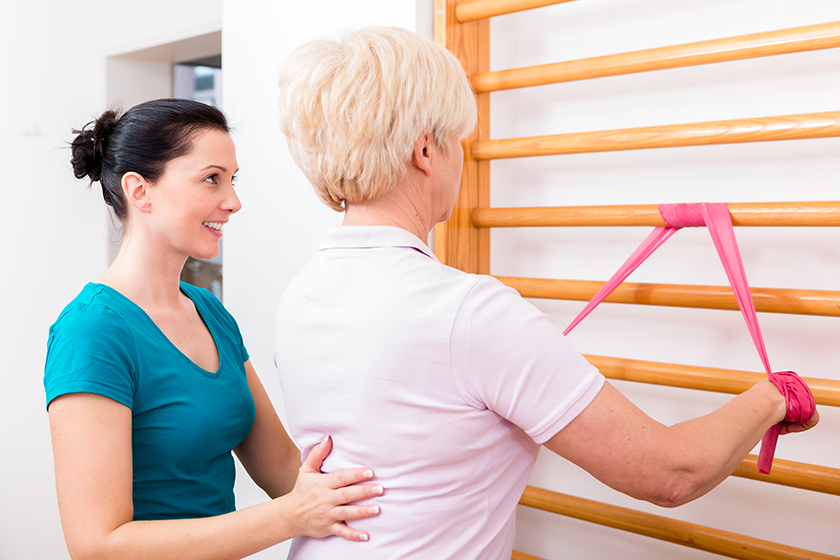 physio-assisting-elderly-woman-during-exercise-with-power-band