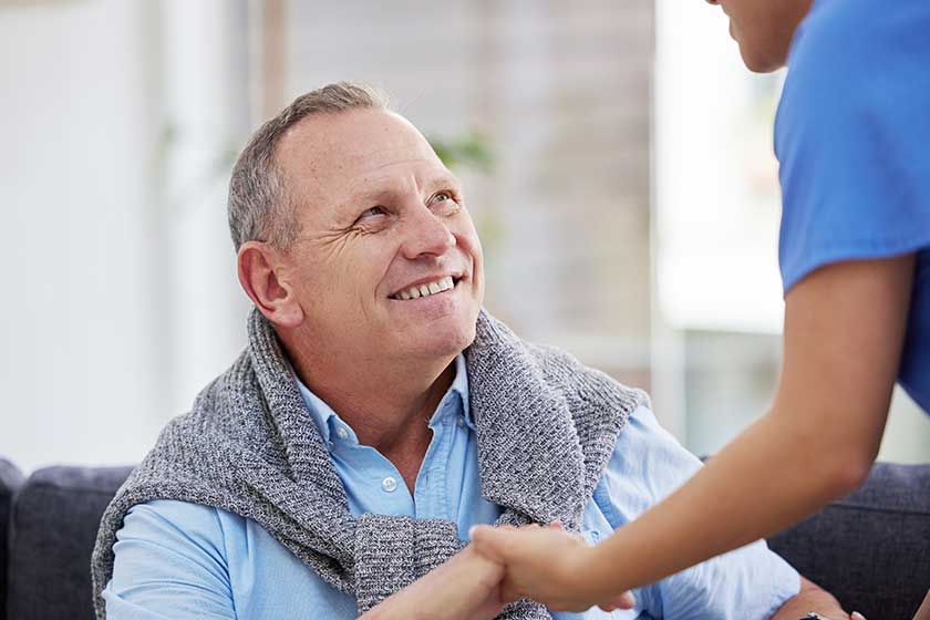 A senior man sitting in the clinic while his nurse helps him.